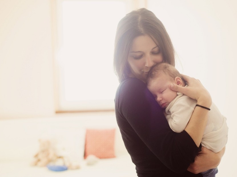 Mulher no pós-parto com bebê no colo.